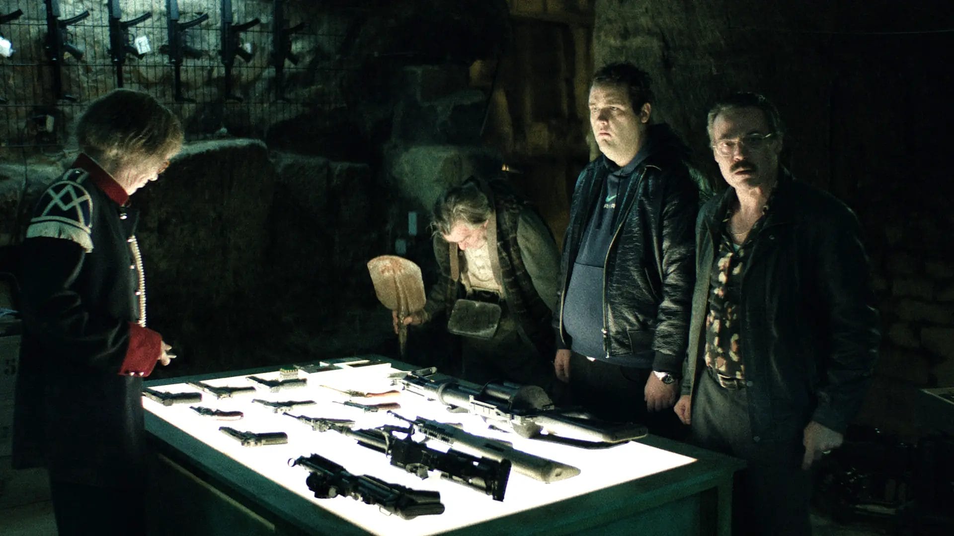 Men examining weapons in dim light.